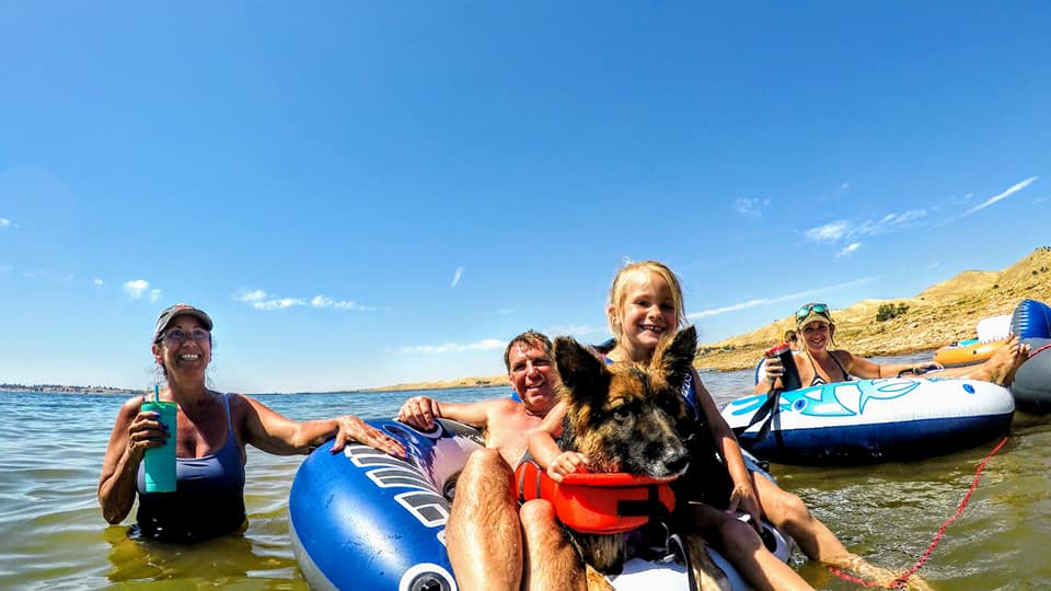 Pat Albert floating on the lake with family and the dog